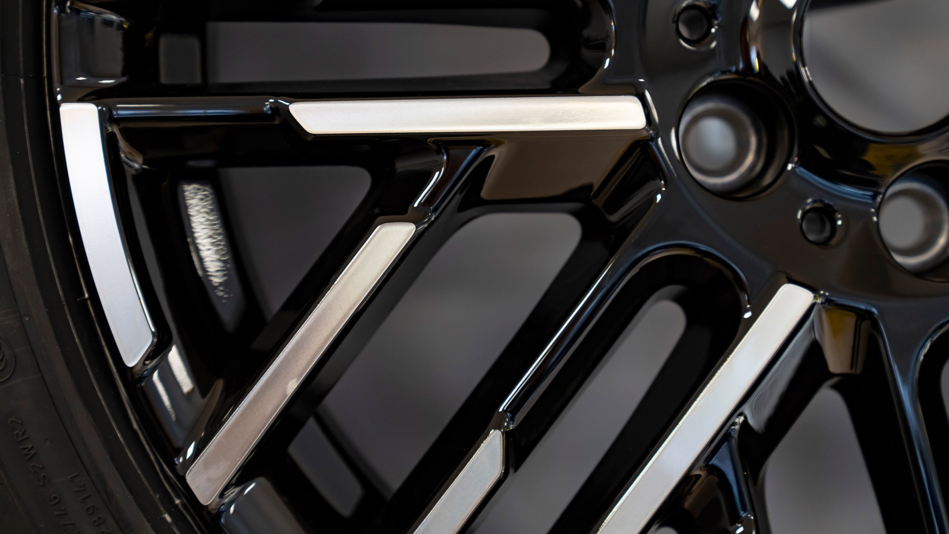 Close‑up of the All‑Electric MINI Cooper’s black and silver alloy wheel with a high‑gloss finish.